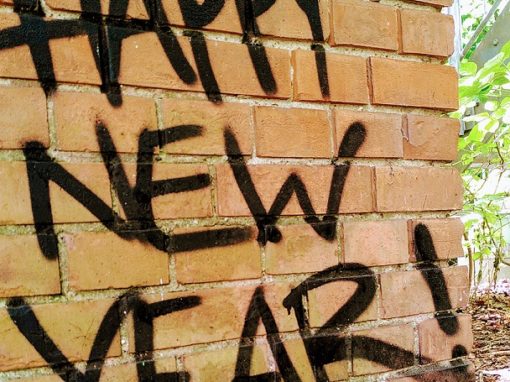 Steinmauer auf der "Hapy New Year" gesprayt ist.