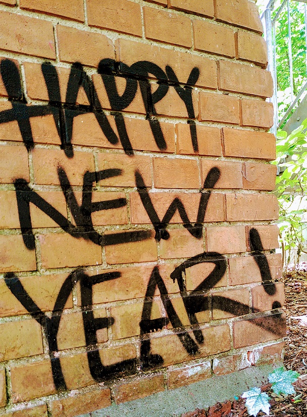 Steinmauer auf der "Hapy New Year" gesprayt ist.